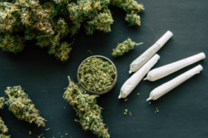 4 Joints liegen neben Cannabisblüten auf dem Tisch