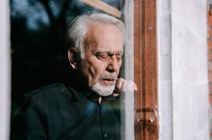 Person sitzt nachdenklich am Fenster waehrend des Cannabis-Entzugs