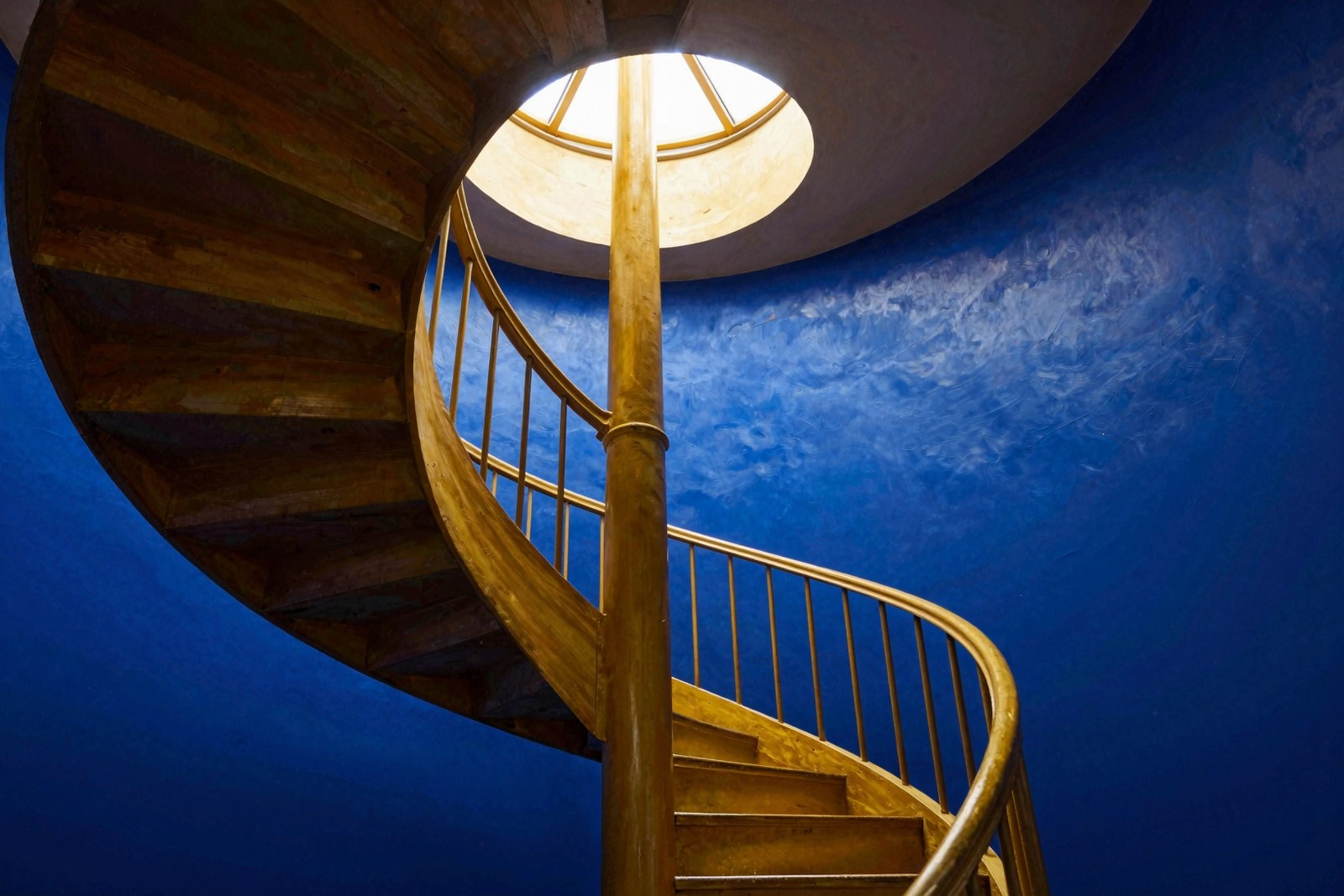 Wendeltreppe mit Licht von oben vor blauer Wand